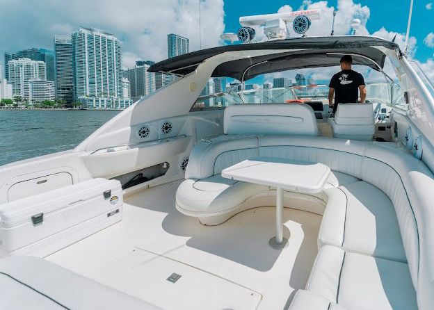 A man is standing on the back of a white yacht.