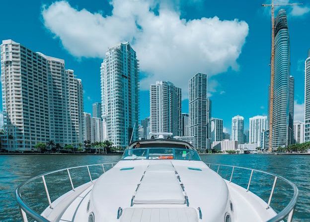 A boat is floating on a body of water with a city in the background.