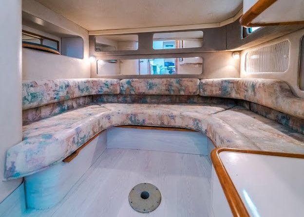 The inside of a boat with a couch and a sink.