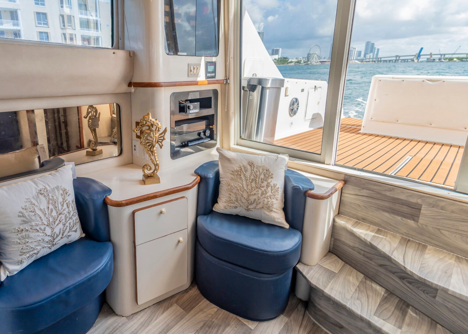 A living room on a boat with a chair and stairs leading to the water.