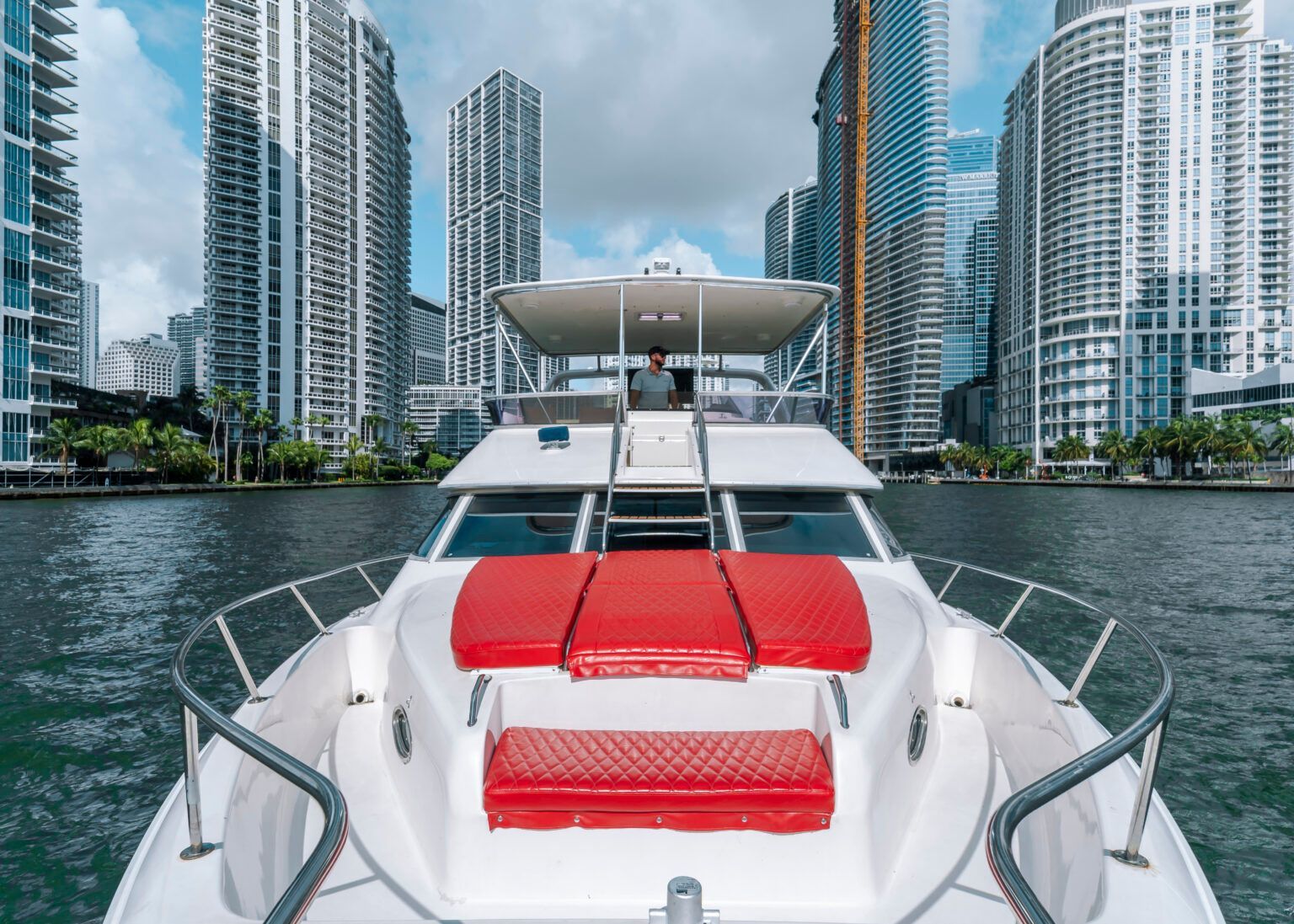 A white yacht is floating on top of a body of water with a city in the background.