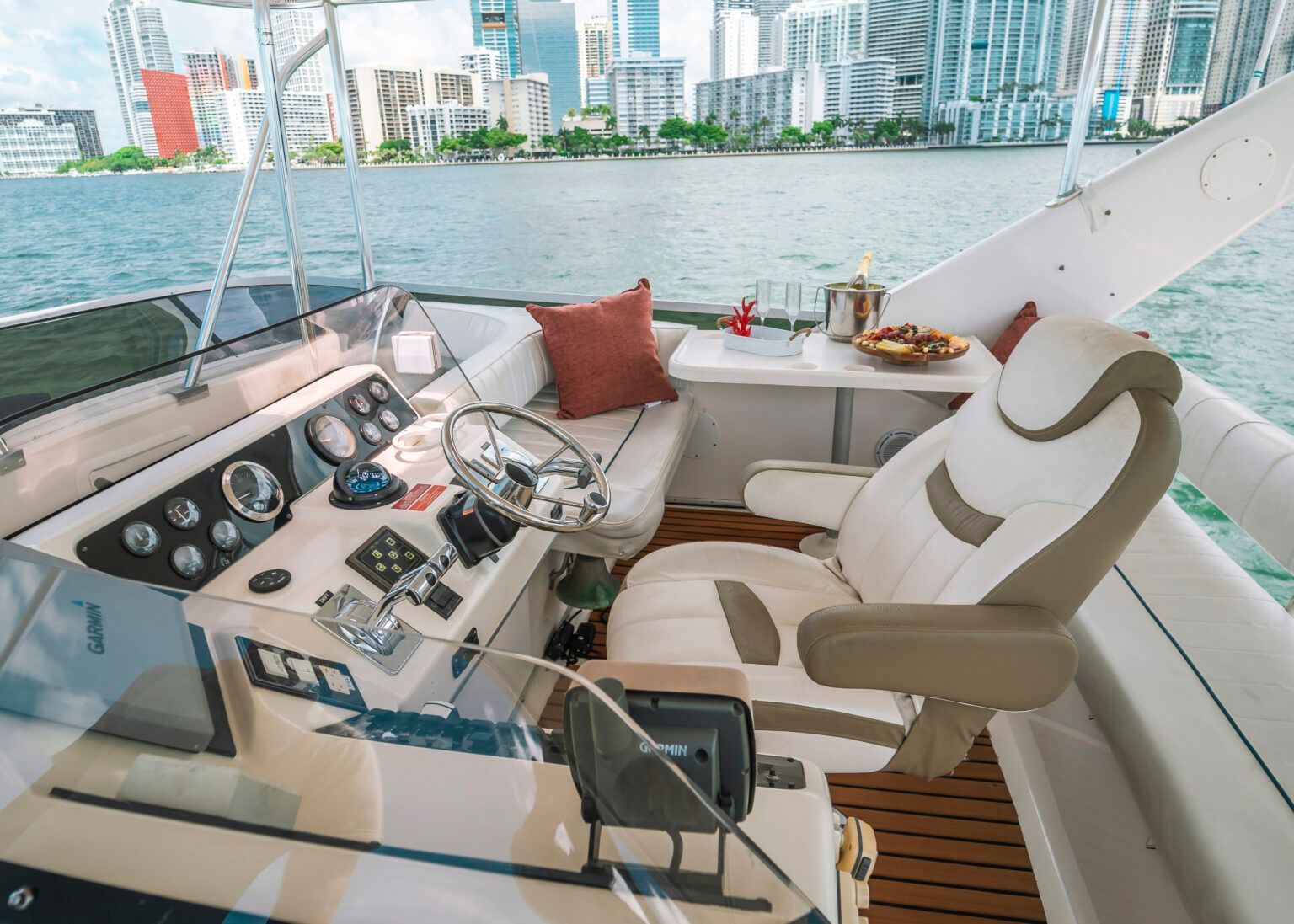 The cockpit of a boat with a steering wheel and a chair.