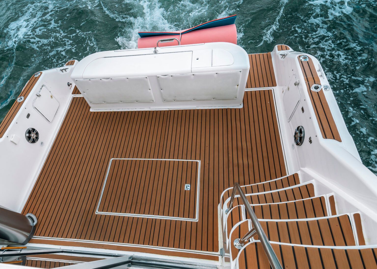 The back of a boat with a wooden deck and stairs.