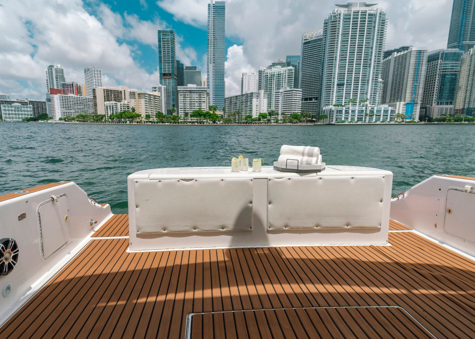 The back of a boat with a table on it and a city in the background.