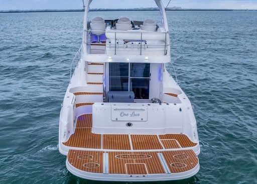 A white boat with a wooden deck is floating on top of a body of water.