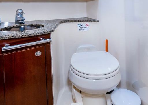 A bathroom with a toilet, sink and trash can.