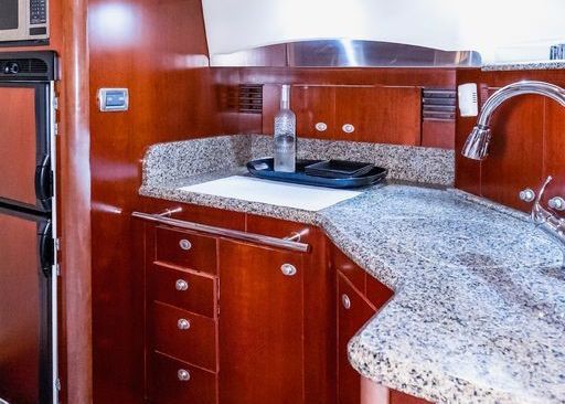 A kitchen on a boat with granite counter tops and wooden cabinets.