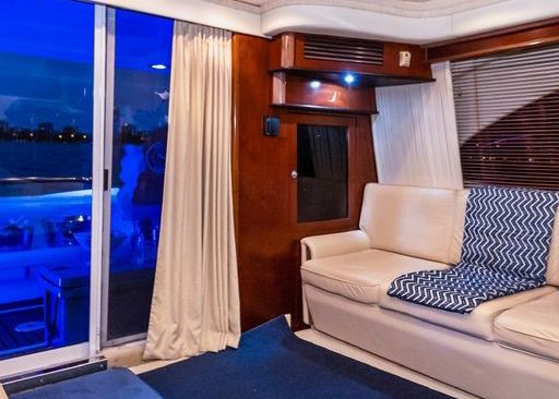 A living room on a boat with a couch and a sliding glass door.