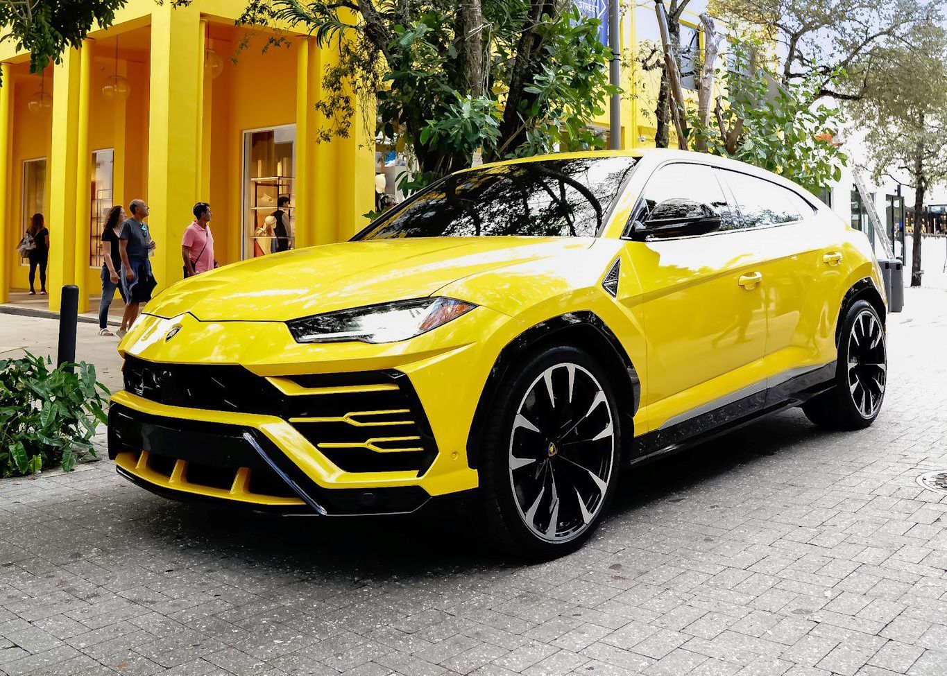 A yellow Lamborghini Urus is parked in front of a yellow building.