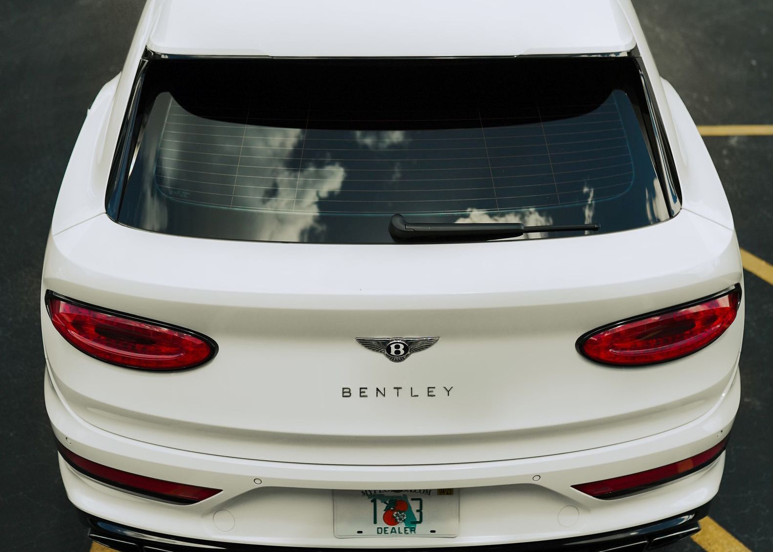 A white Bentley is parked in a parking lot.