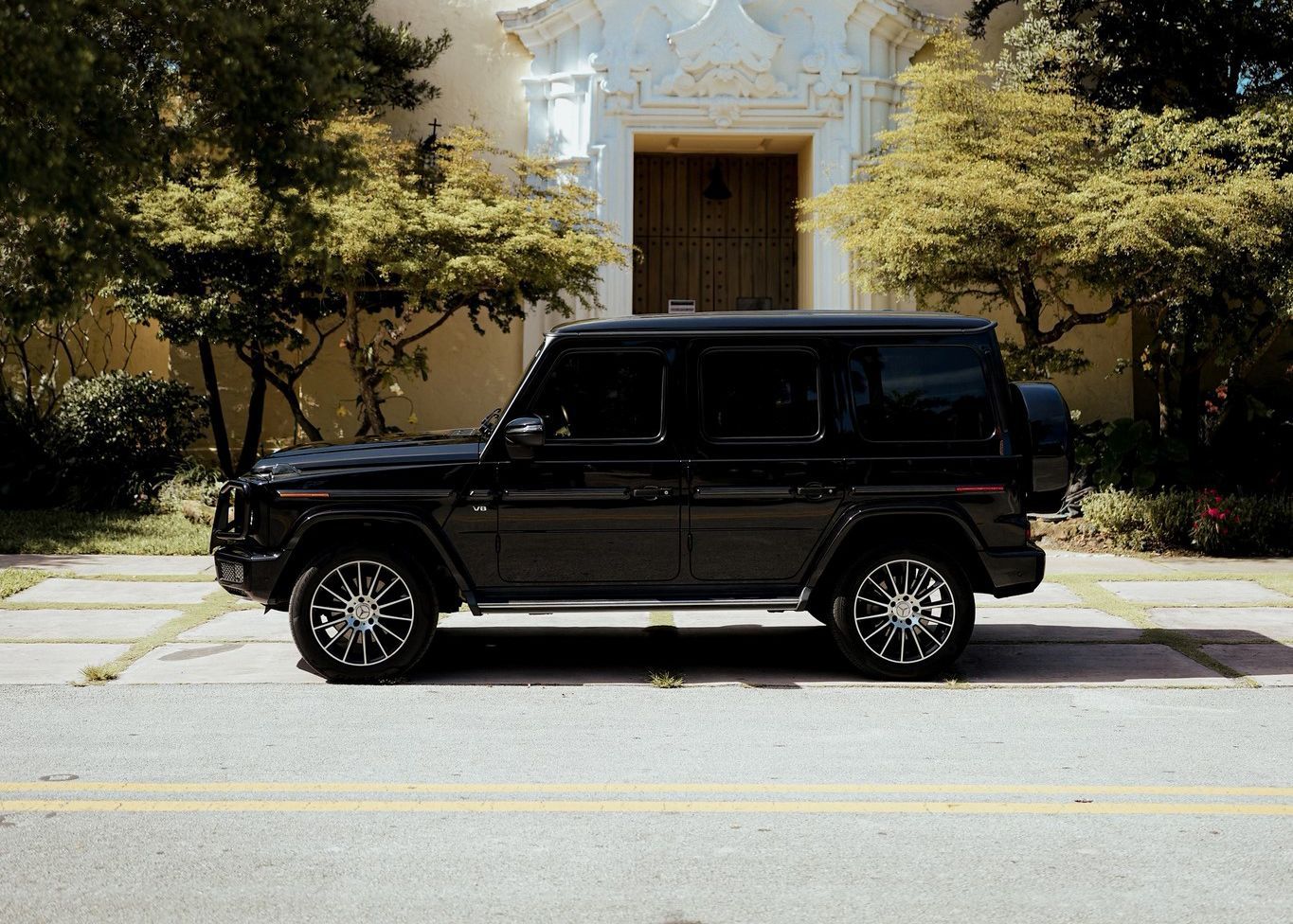 A black SUV is parked on the side of the road in front of a building.