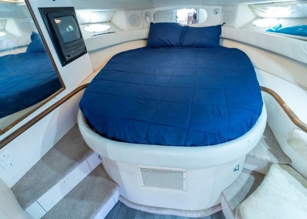 A round bed with a blue blanket on a boat.