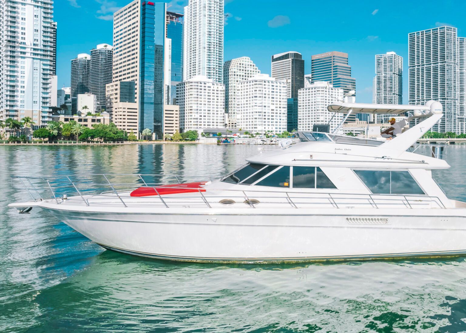 A white yacht is floating on top of a body of water in front of a city skyline.