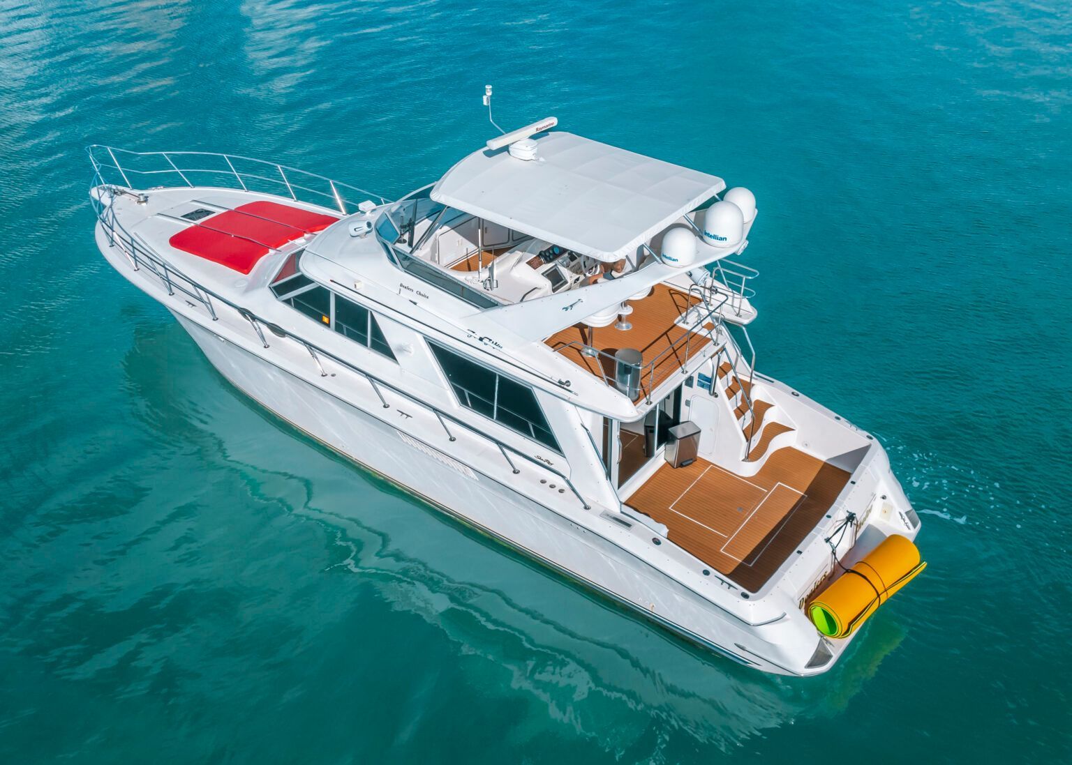 A white yacht with a red roof is floating on top of a body of water.