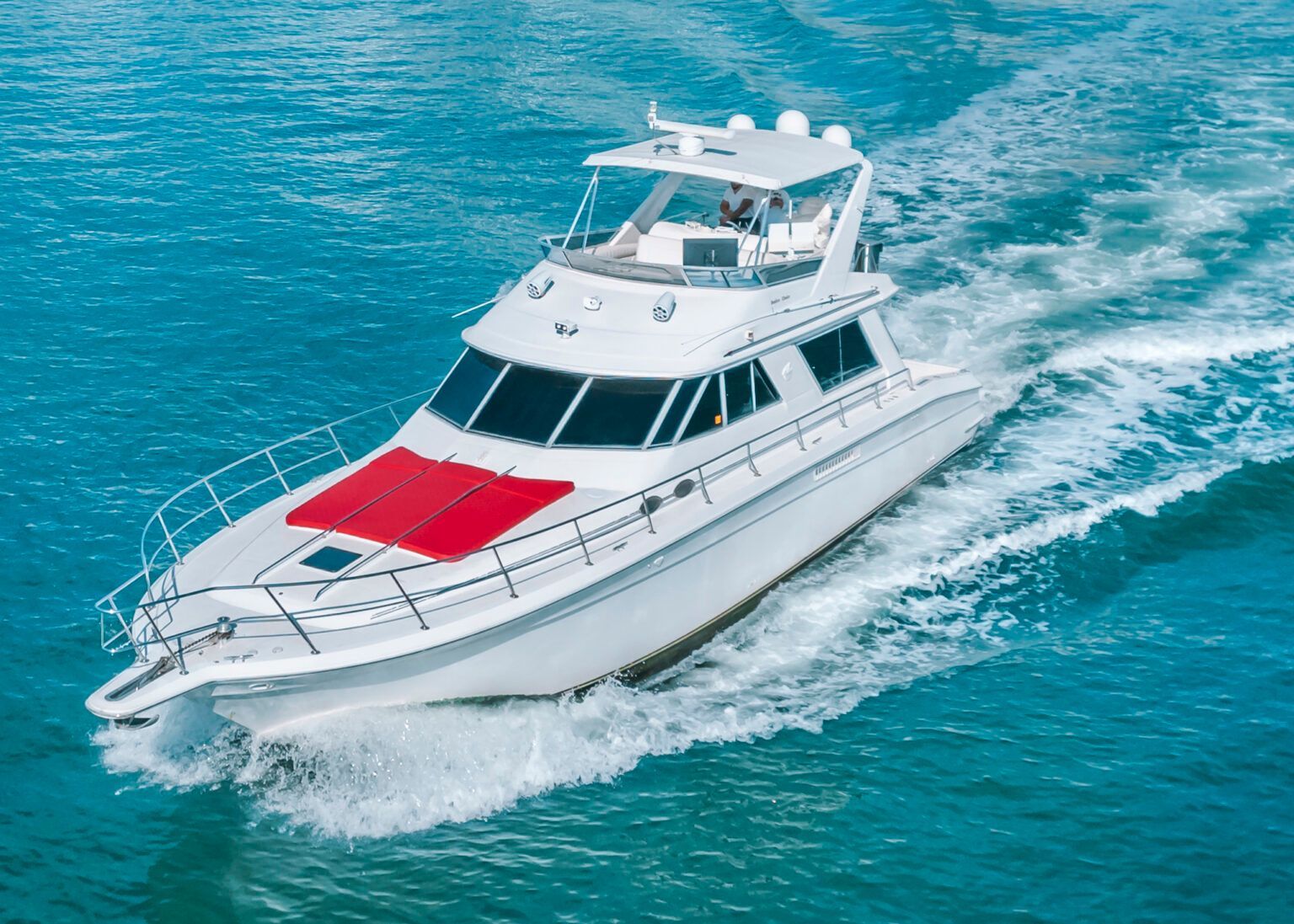 A white boat with a red blanket on the deck is floating on top of a body of water.