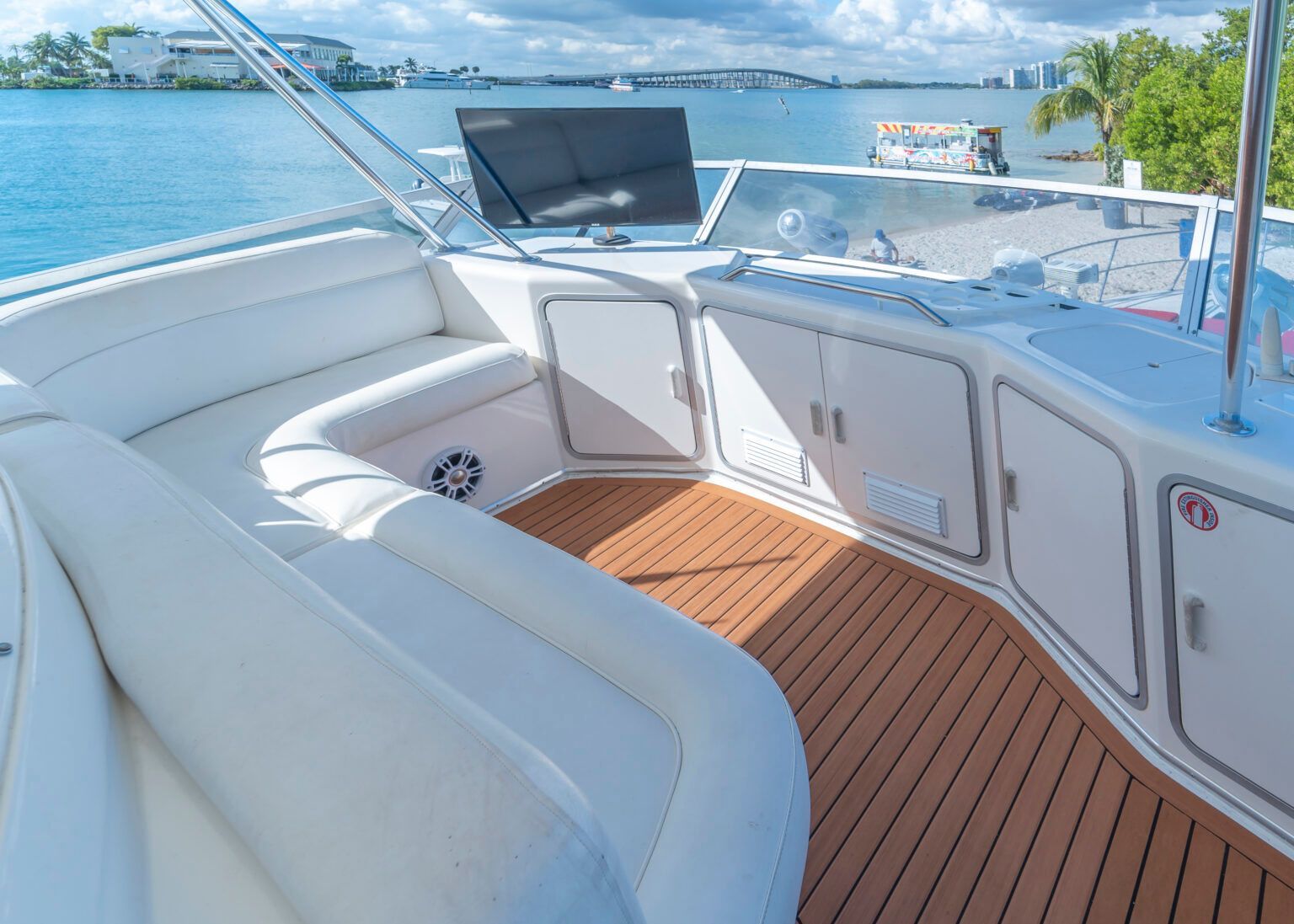 The inside of a boat with a wooden deck and white seats.