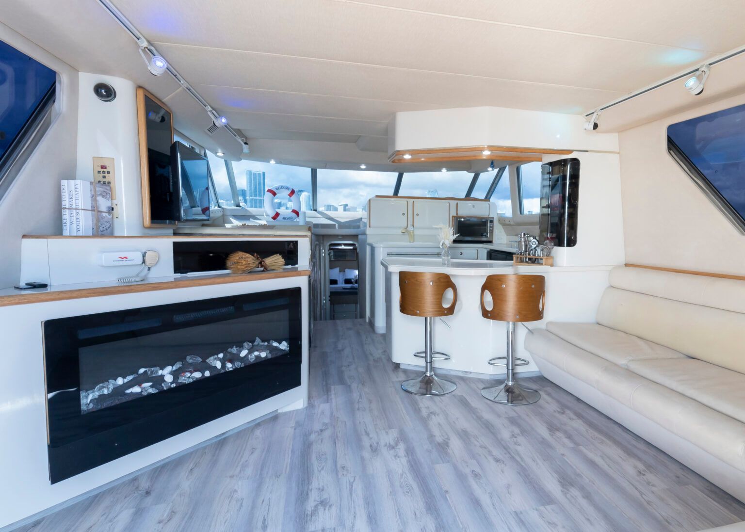 A living room on a boat with a fireplace and stools.