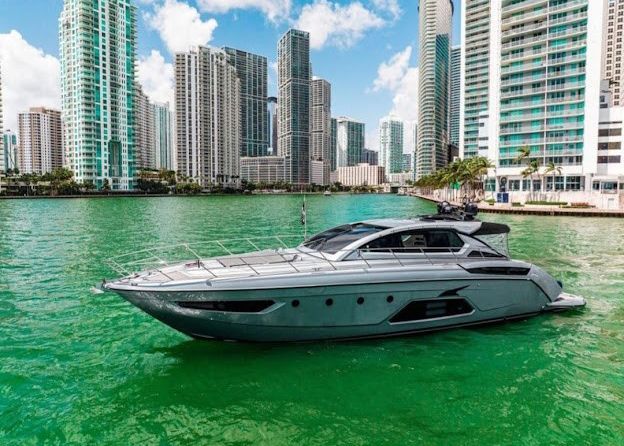 A yacht is floating on top of a body of water in front of a city.