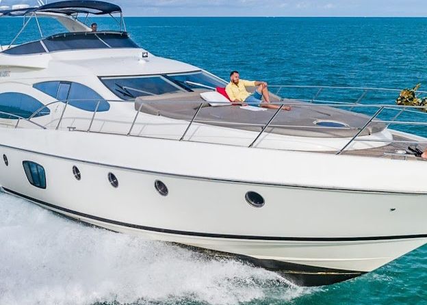 A man is sitting on the deck of a yacht in the ocean.