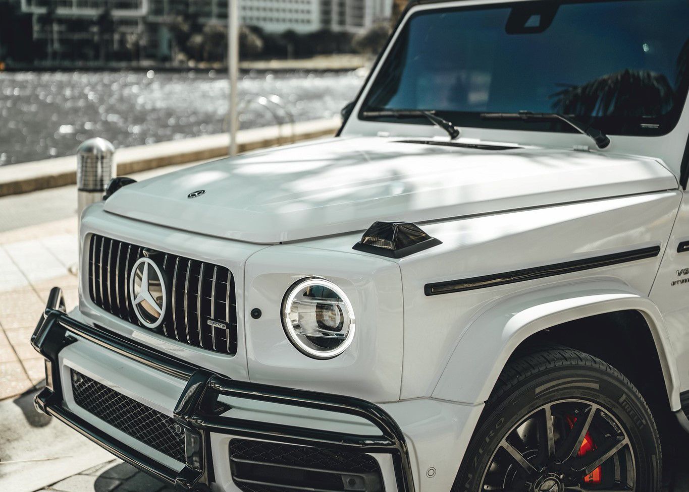 A white Mercedes Benz G550 is parked on the side of the road.