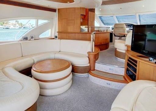 A living room on a boat with white furniture and a flat screen TV.