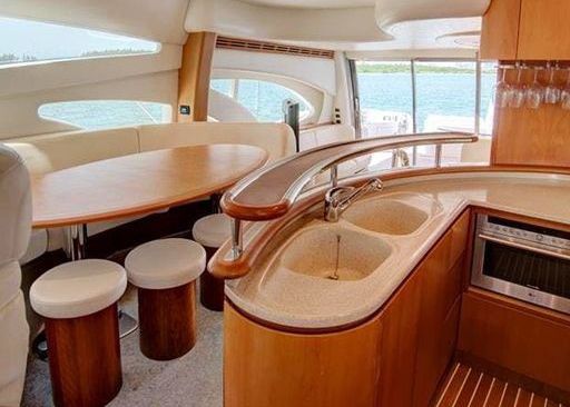 A kitchen on a boat with a sink, table and stools.