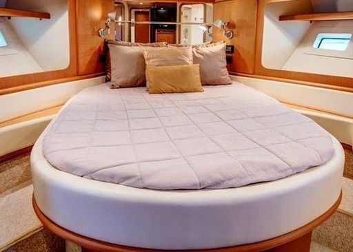 A round bed with purple sheets and pillows on a boat.