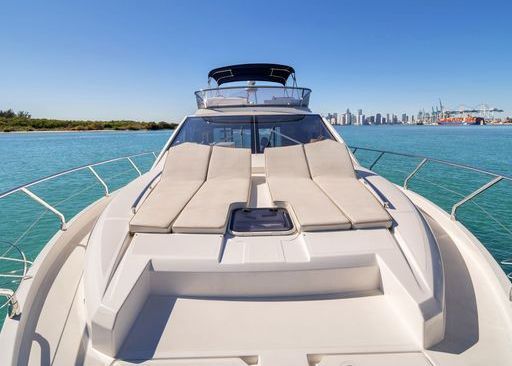 The front of a white yacht is floating on top of a body of water.