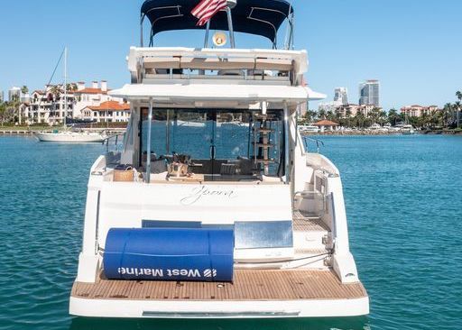 The back of a white yacht is floating on top of a body of water.