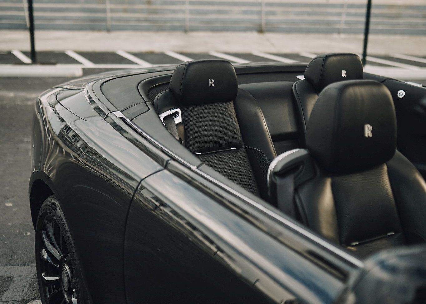 A black convertible car is parked in a parking lot.