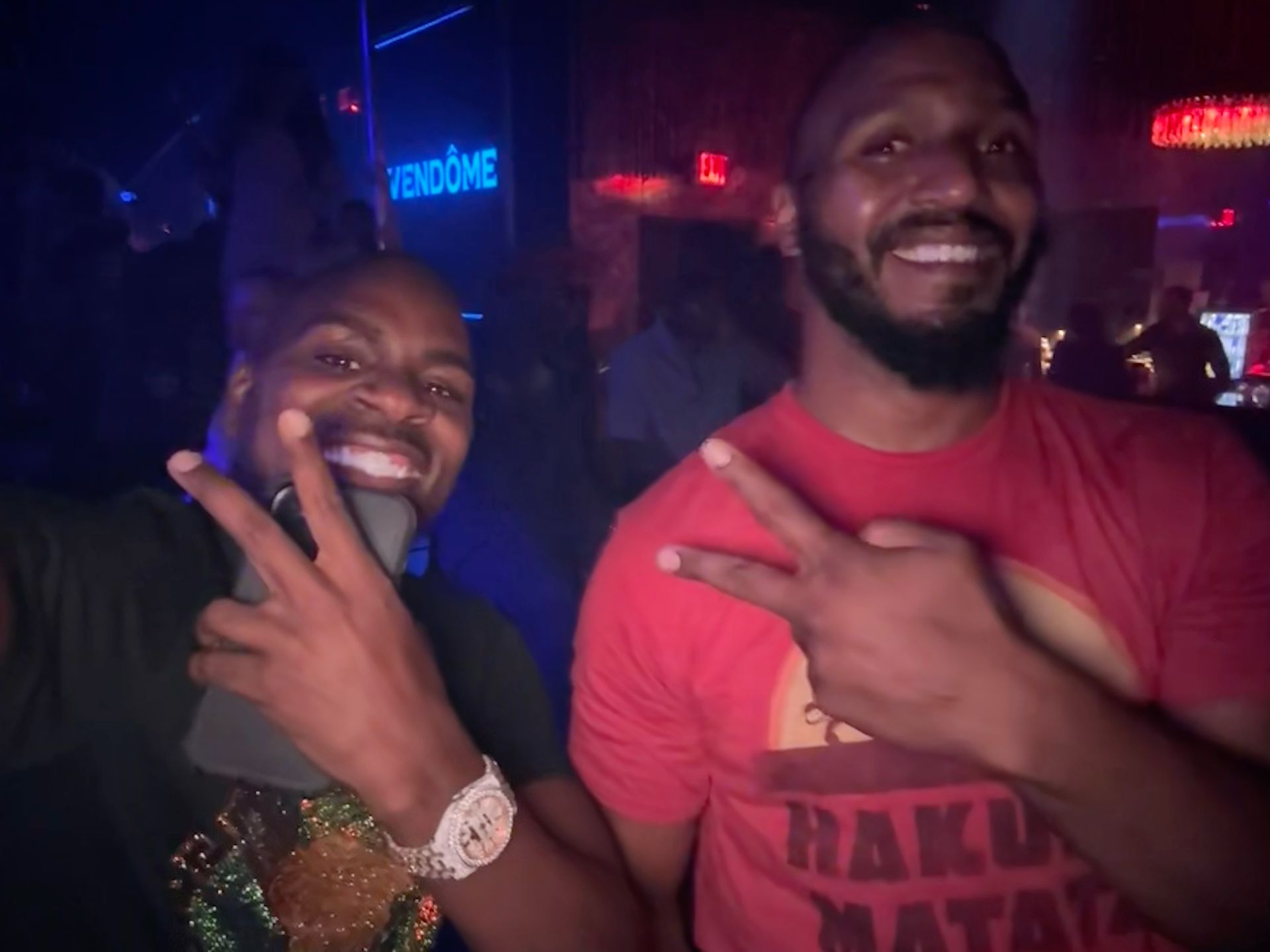 Two men are standing next to each other and one of them is wearing a shirt that says hakuna matata