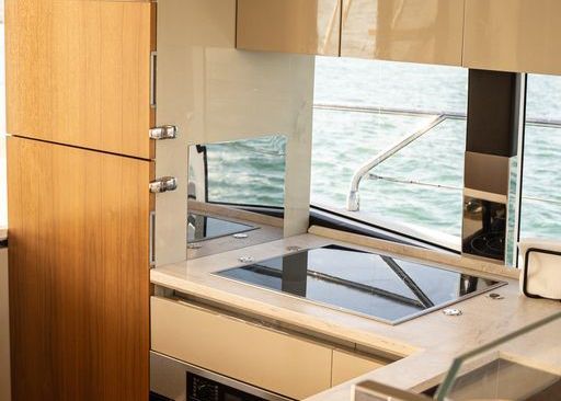 A kitchen on a boat with a stove top oven and a refrigerator.