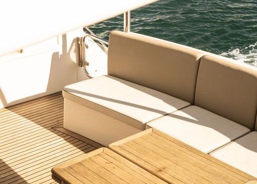 There is a couch and a table on the deck of a boat.