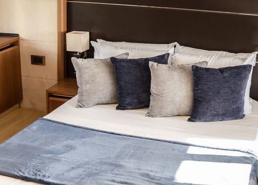 A bed with blue and gray pillows on it in a hotel room.