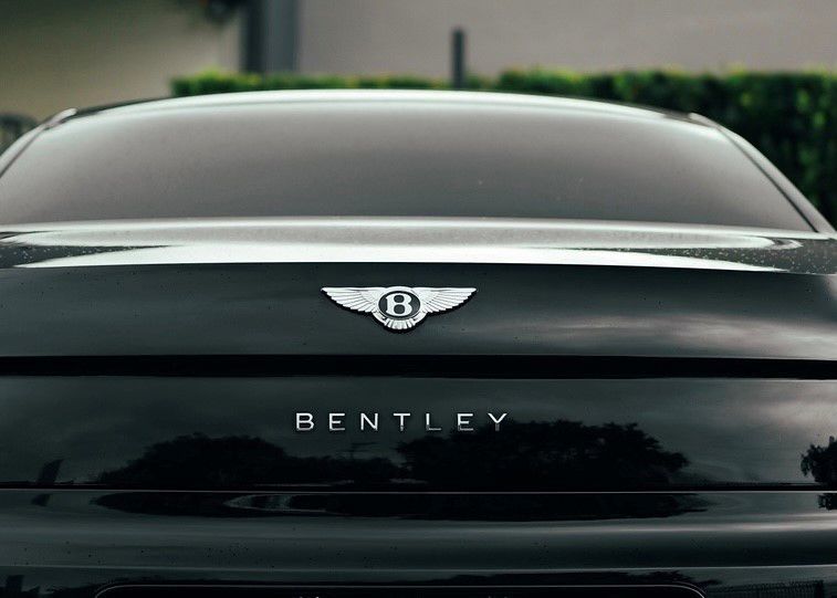 A black Bentley car is parked in front of a building.