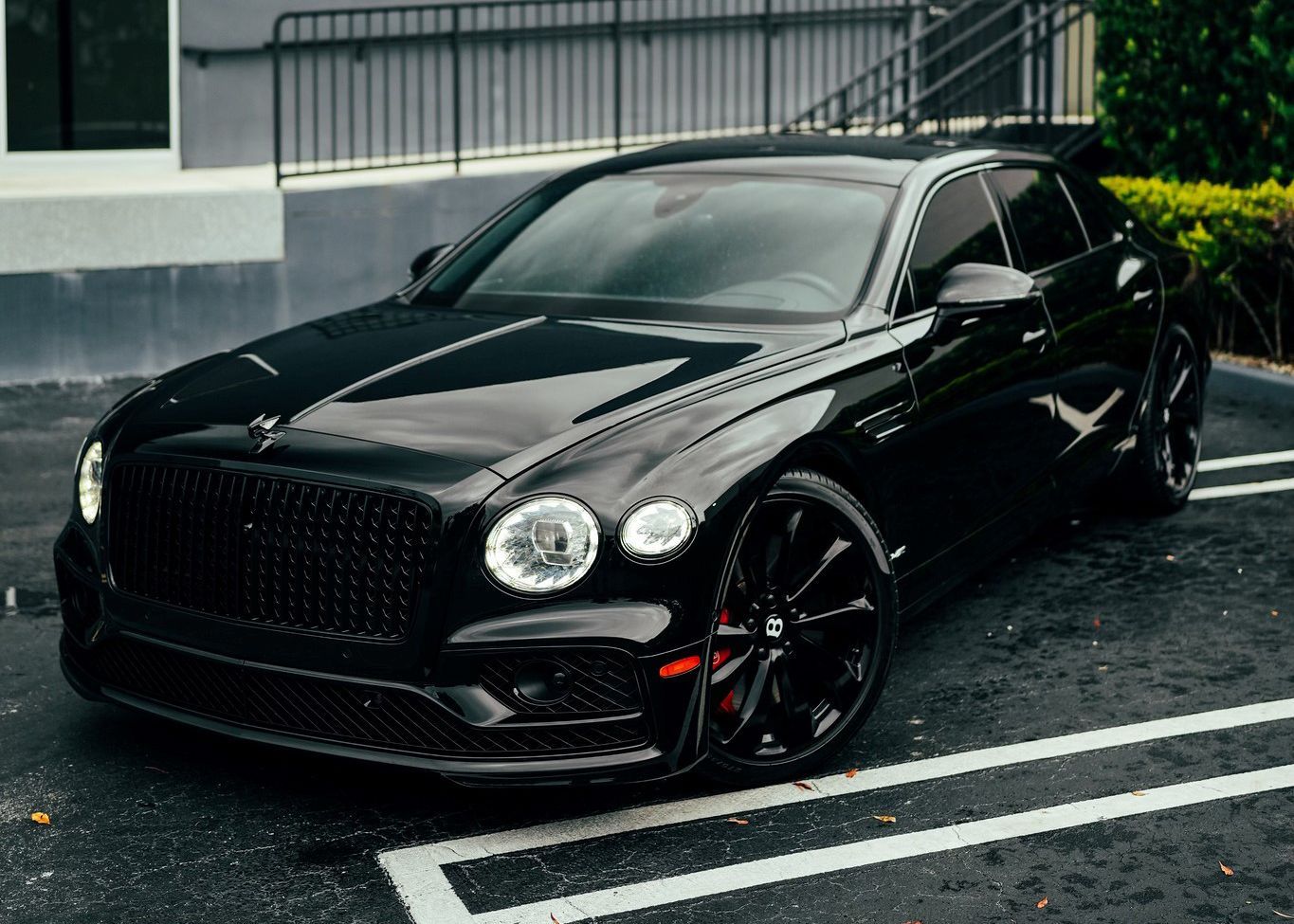 A black Bentley Flying Spur is parked in a parking lot.
