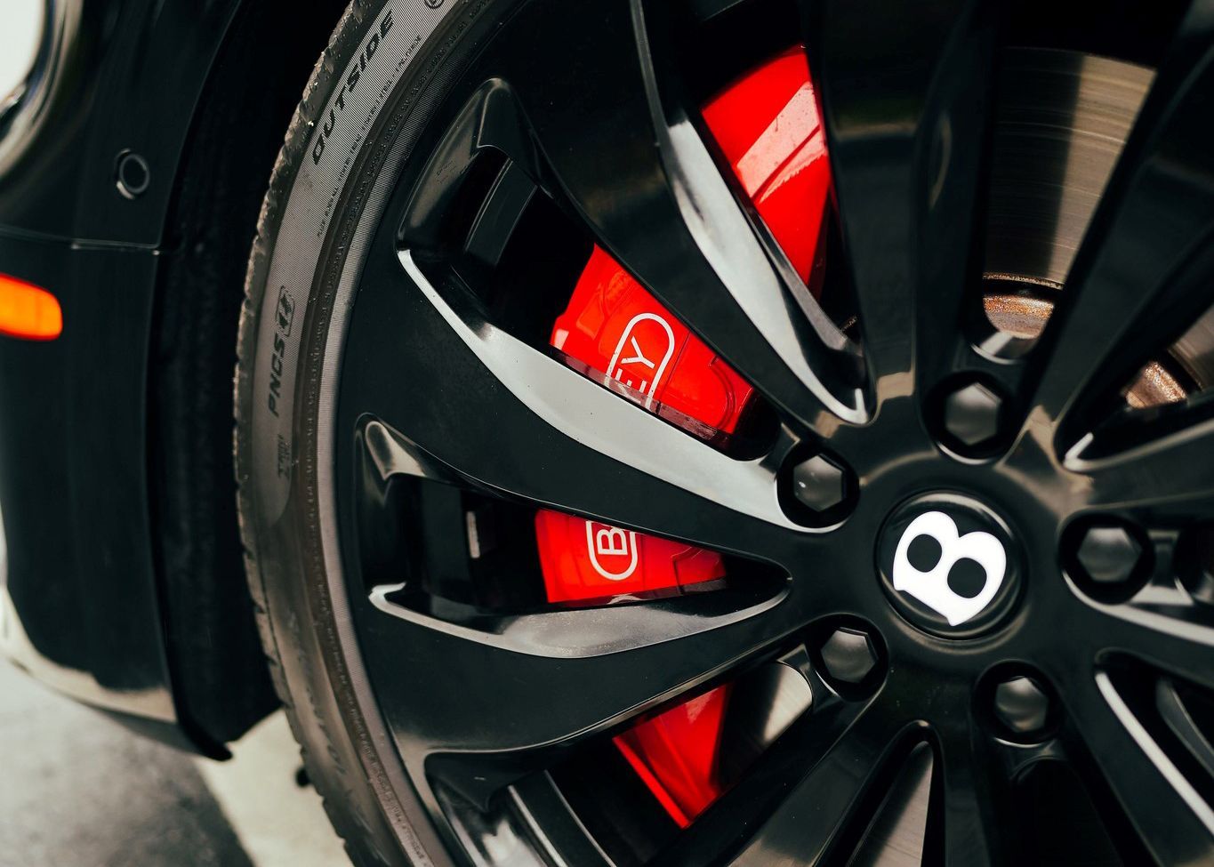 A close up of a black car wheel with red brake calipers.