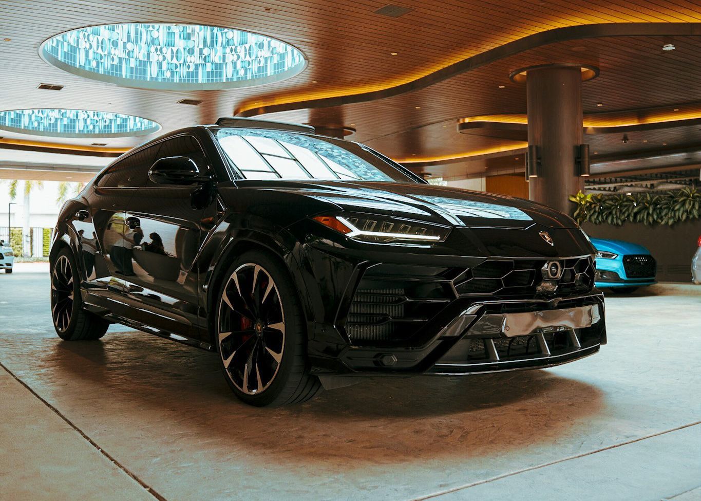 A black Lamborghini Urus is parked in a parking garage.