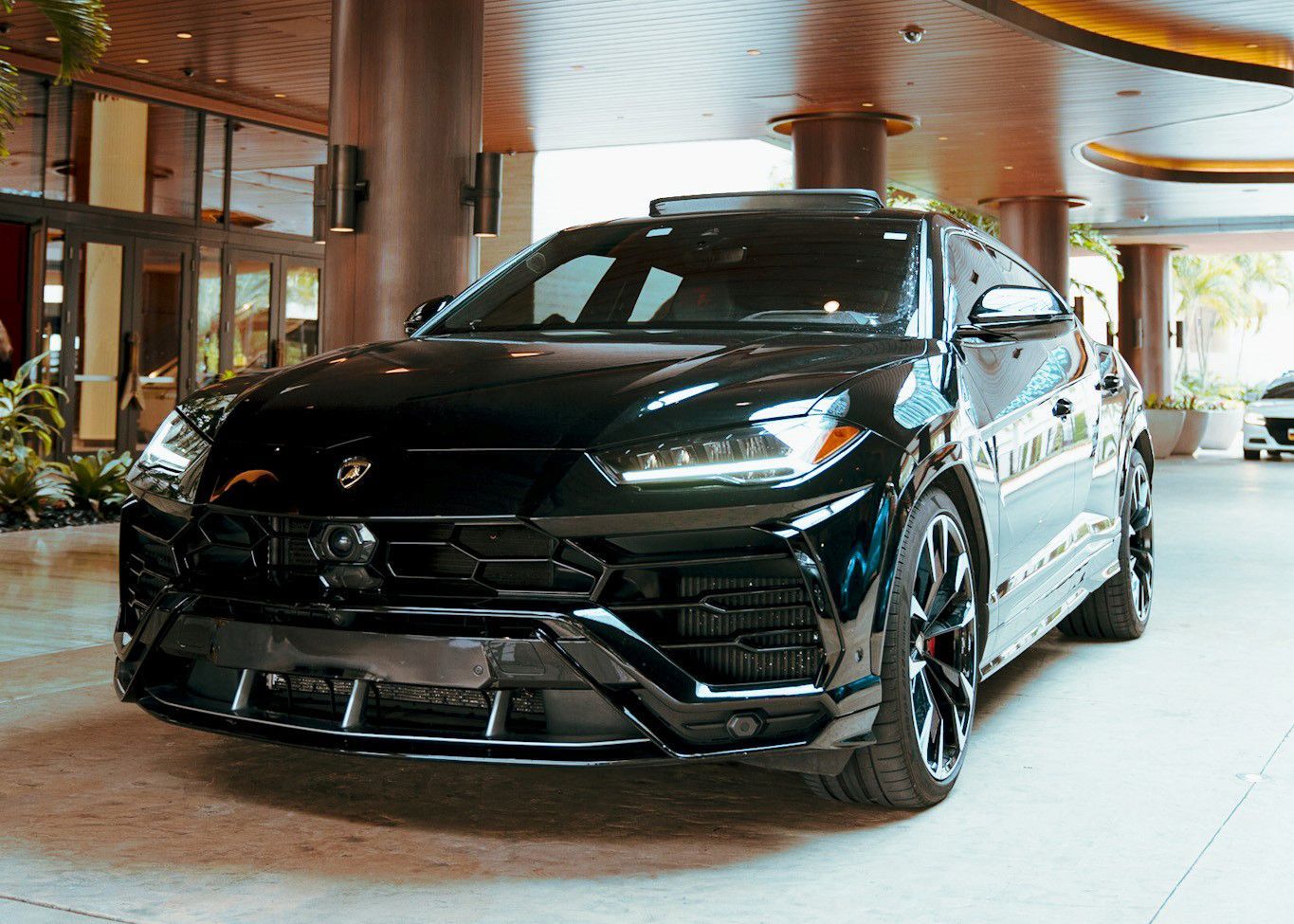 A black Lamborghini Urus is parked in a parking lot.
