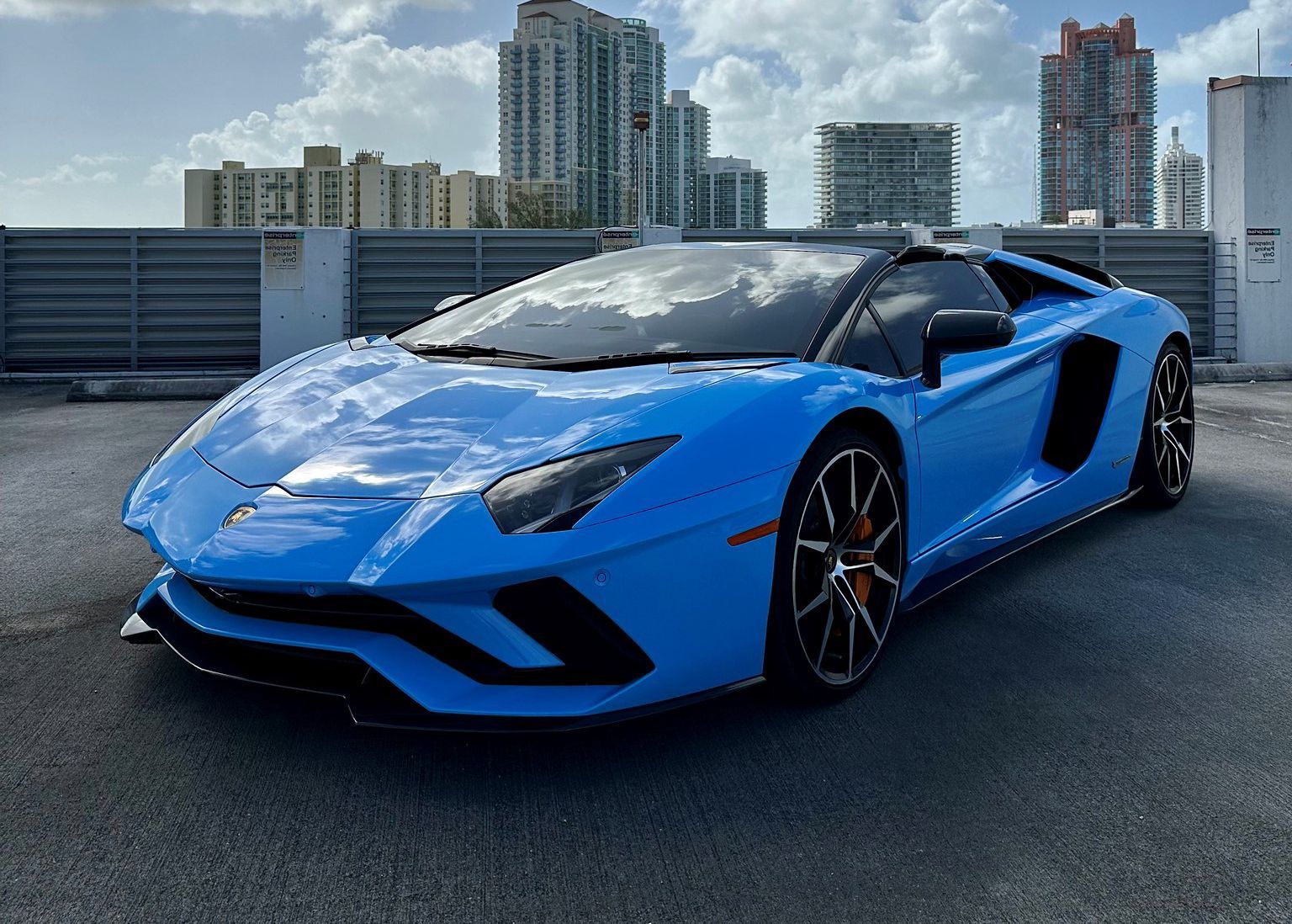 A blue Lamborghini Aventador is parked in a parking lot.