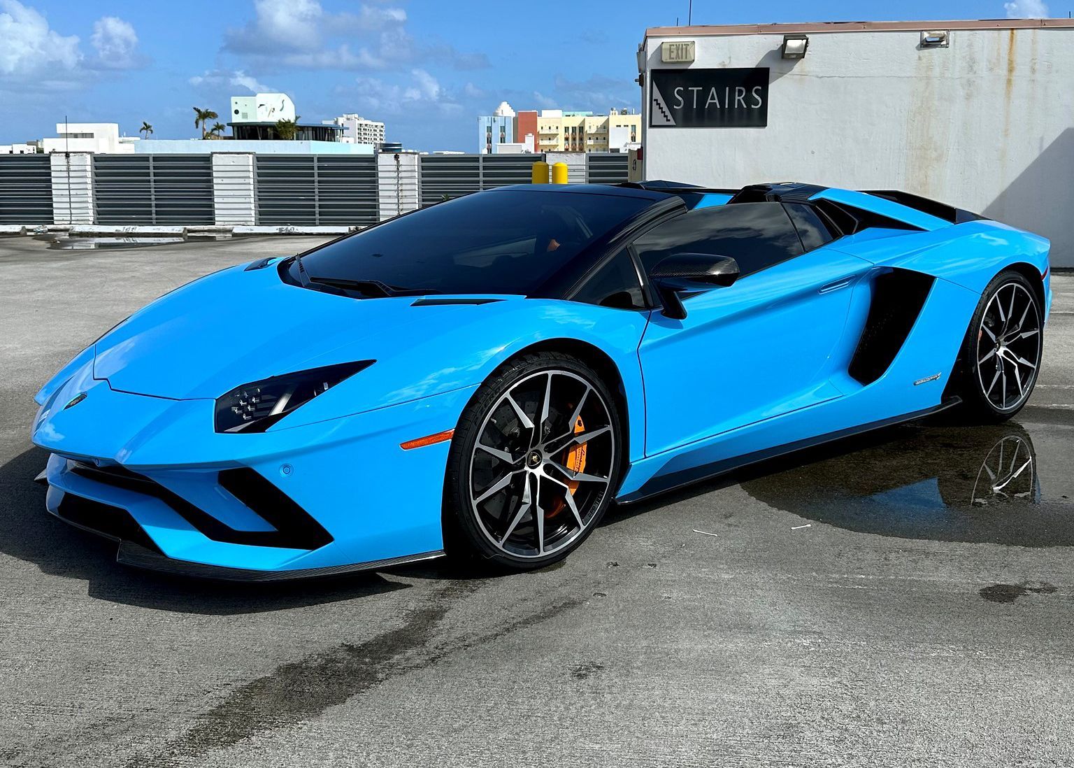 A blue Lamborghini Aventador is parked in front of a building.