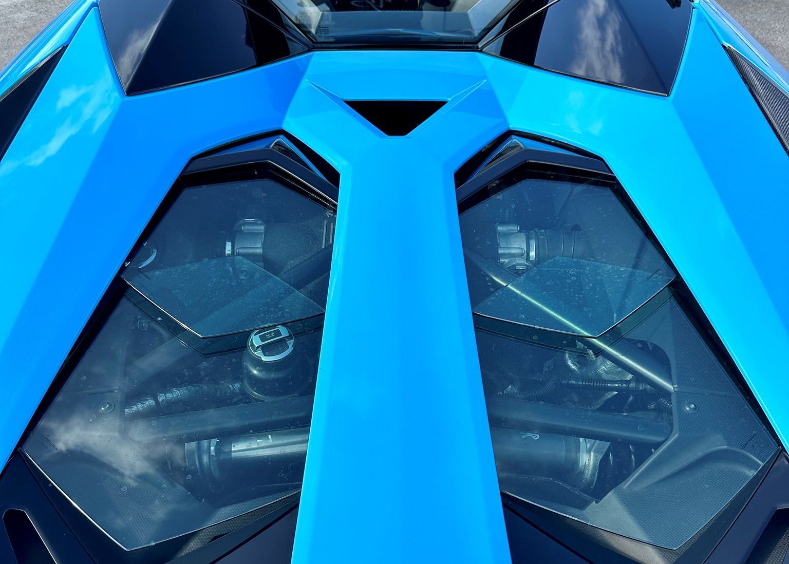 A close up of the engine of a blue sports car.