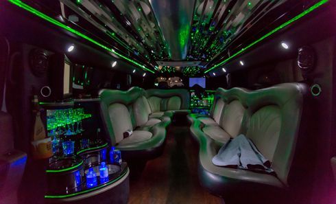 The inside of a party bus with green lights on the ceiling.