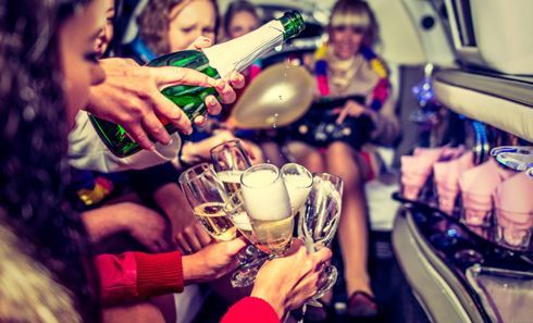 A group of people are pouring champagne into glasses in a party bus.