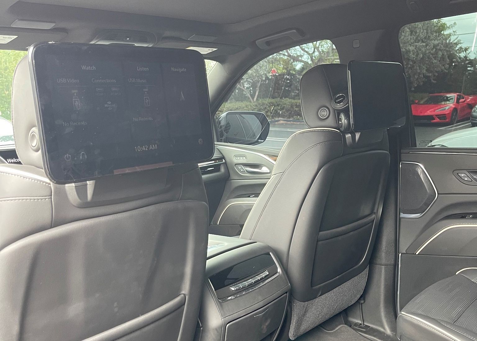 The back seat of a car with two headrest monitors.