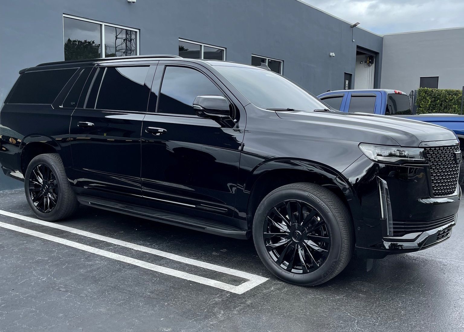 A black SUV is parked in a parking lot in front of a building.