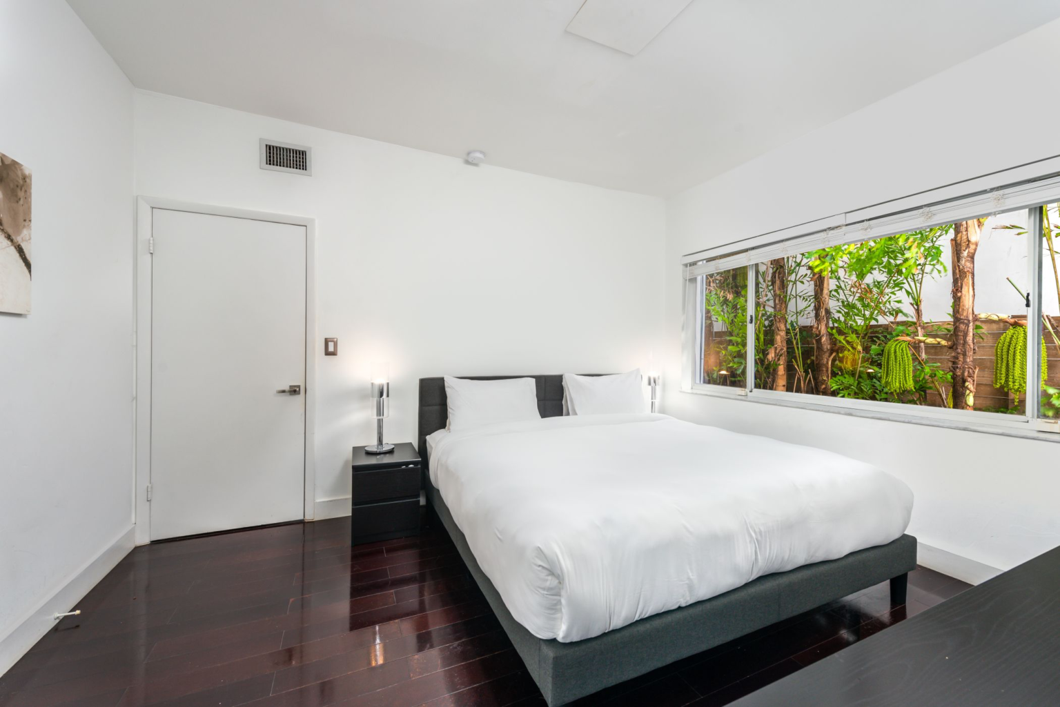 A bedroom with a bed, nightstand, and window.