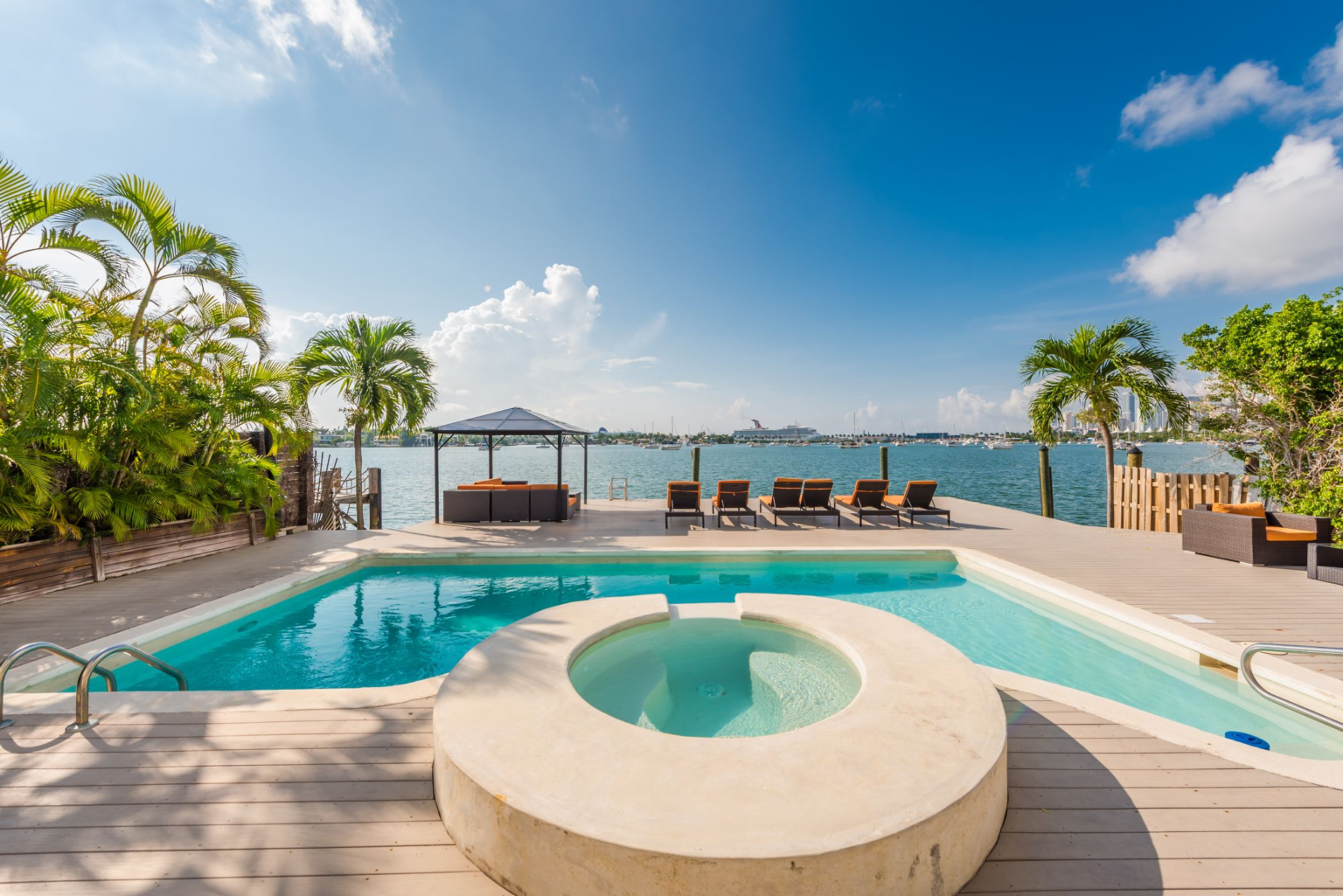 There is a large swimming pool with a hot tub in the middle of it.