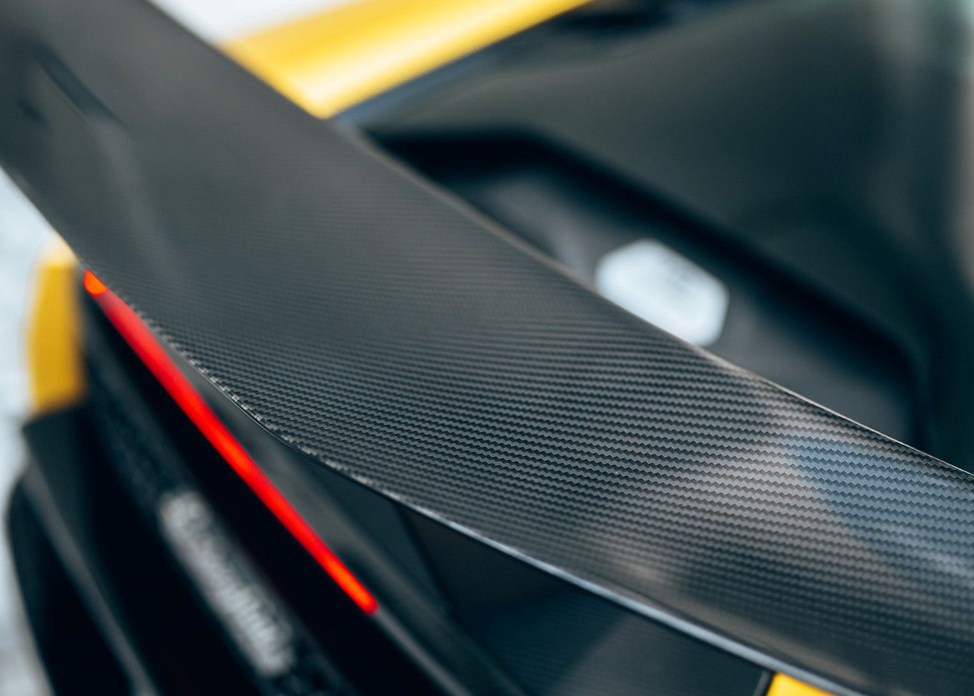 A close up of the rear wing of a black and yellow sports car.