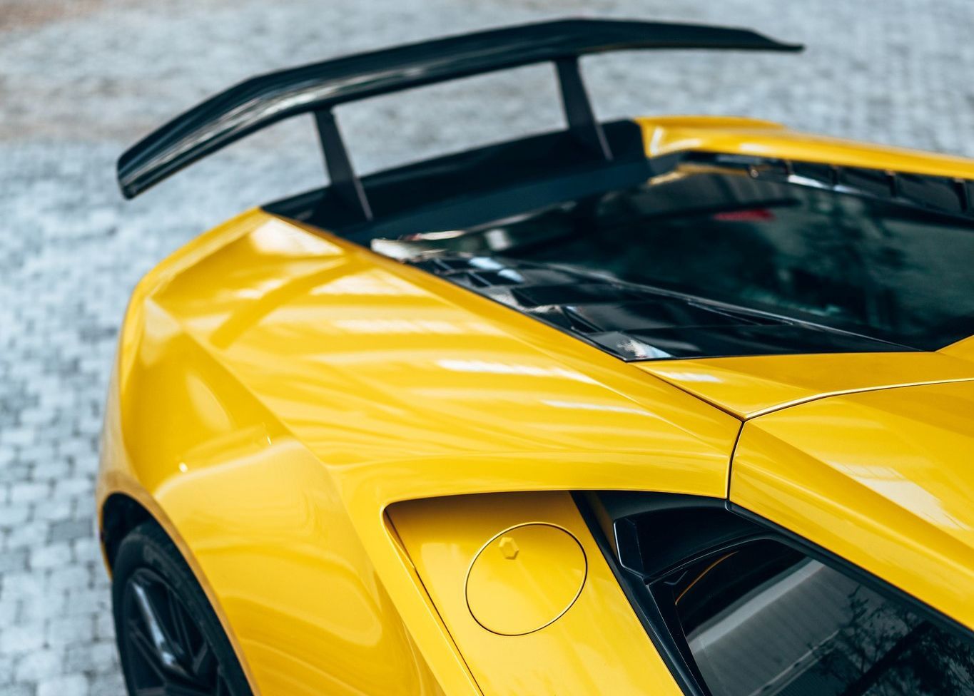 A close up of a yellow sports car with a black wing.